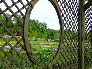 Wood lattice with oval cutout looking out on a colorful garden