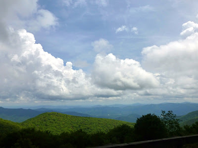 White clouds in the sky above green mountain ridges