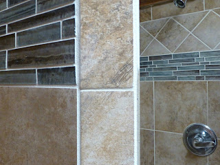 Shower walls with beige tile and blue glass tile accents