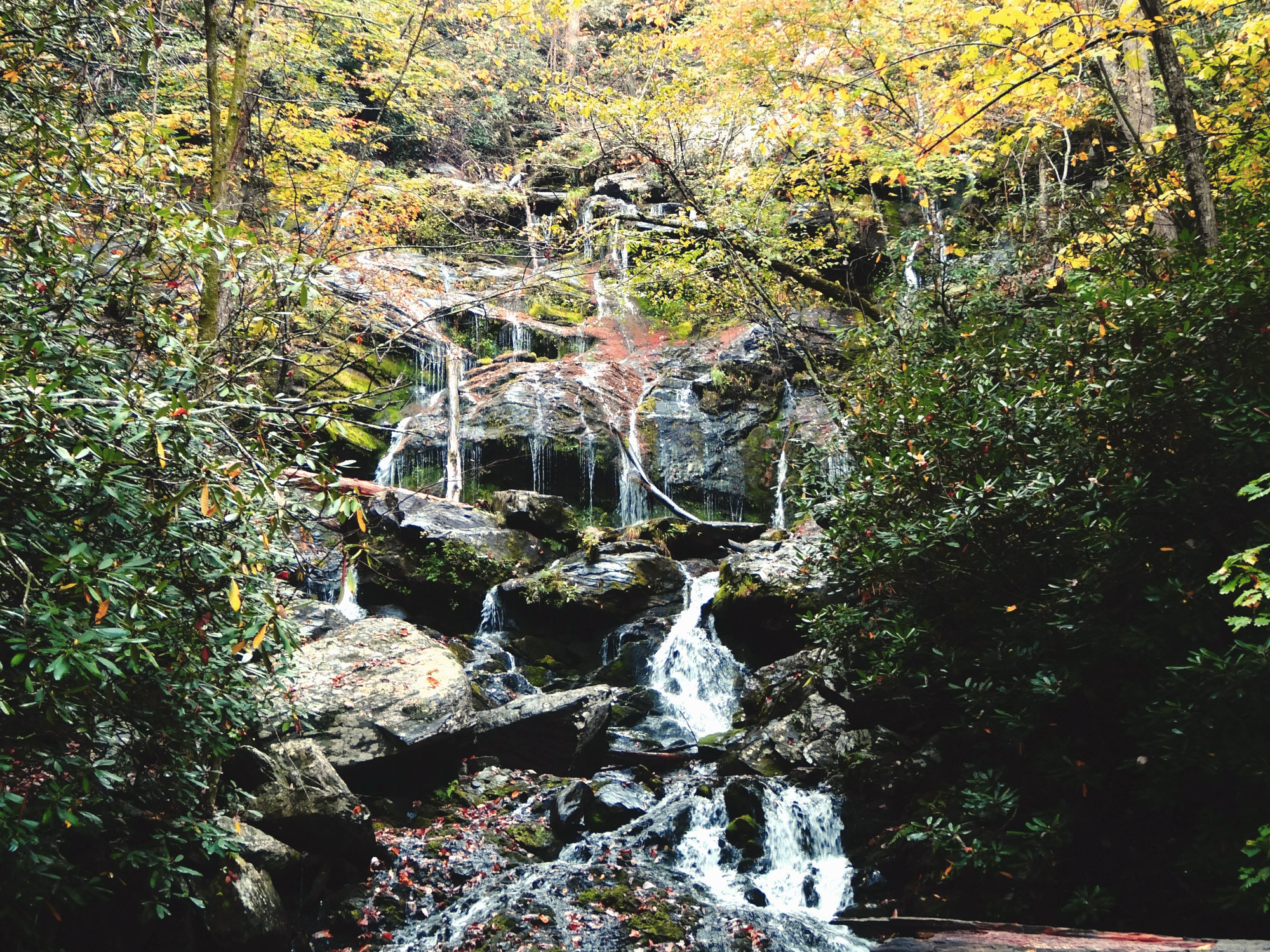 Waterfall with water cascading over huge boulders with greenery all around