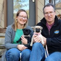 Brigette and Dave sitting on stone stairs at the Inn on Mill Creek Bed & Breakfast with the innpugs, Chibi and Honey