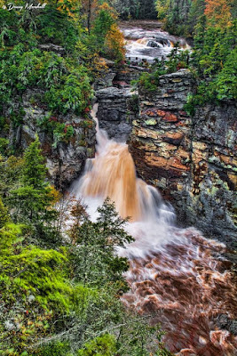 High volume waterfall after a rainfall with muddy water and a raging river