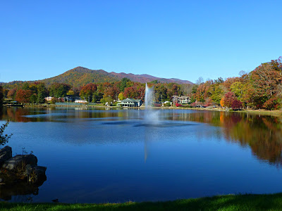 Large blue lake with fall colors on mountains behind it under a blue sky