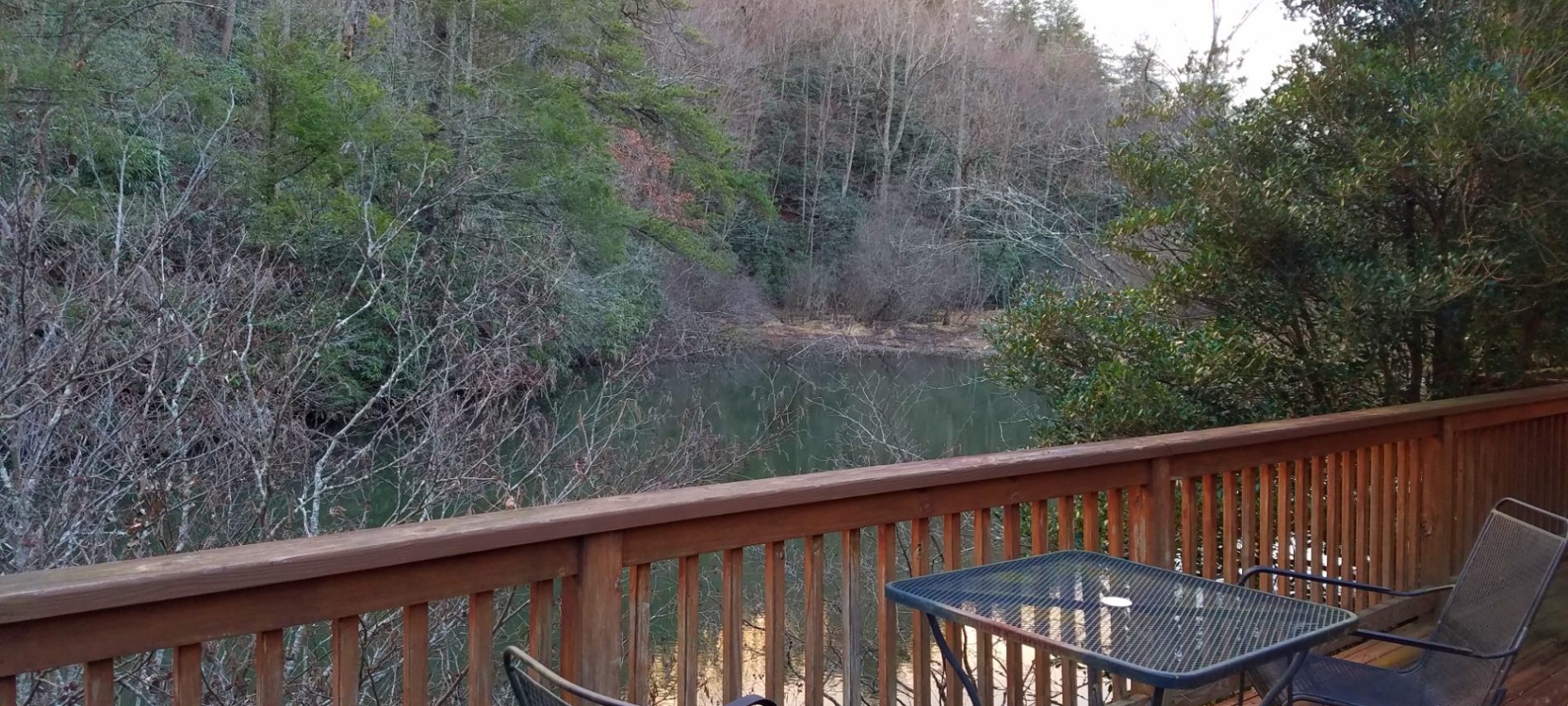 Wrought iron chairs and table on deck overlooking a pond and forest