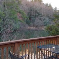 Wrought iron chairs and table on deck overlooking a pond and forest