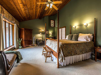 Room with forest green walls and tall windows and large four poster bed