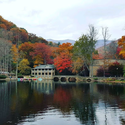 Fall color mountain backdrop and building with several stone columns along a lake