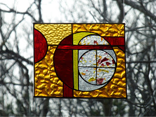 Orange and red stained glass artwork hanging in a window