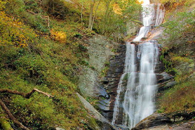 Waterfall dropping down steep granite with green and yellow foliage on either side