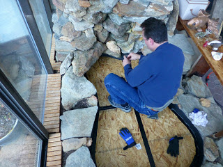 Man applying duct tape to plywood seams in fishpond