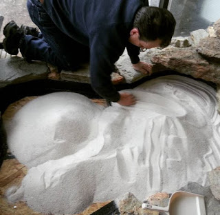 Man spreading sand into small zen garden