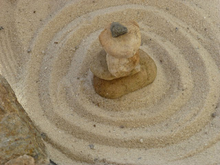 A set of stacked stones with circles of sand around them