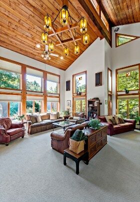 Expansive and bright room with floor to ceiling windows and two-story vaulted wood plank ceiling