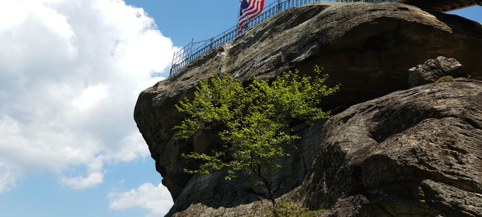 The American flag flies over a large granite monolith