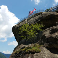 The American flag flies over a large granite monolith