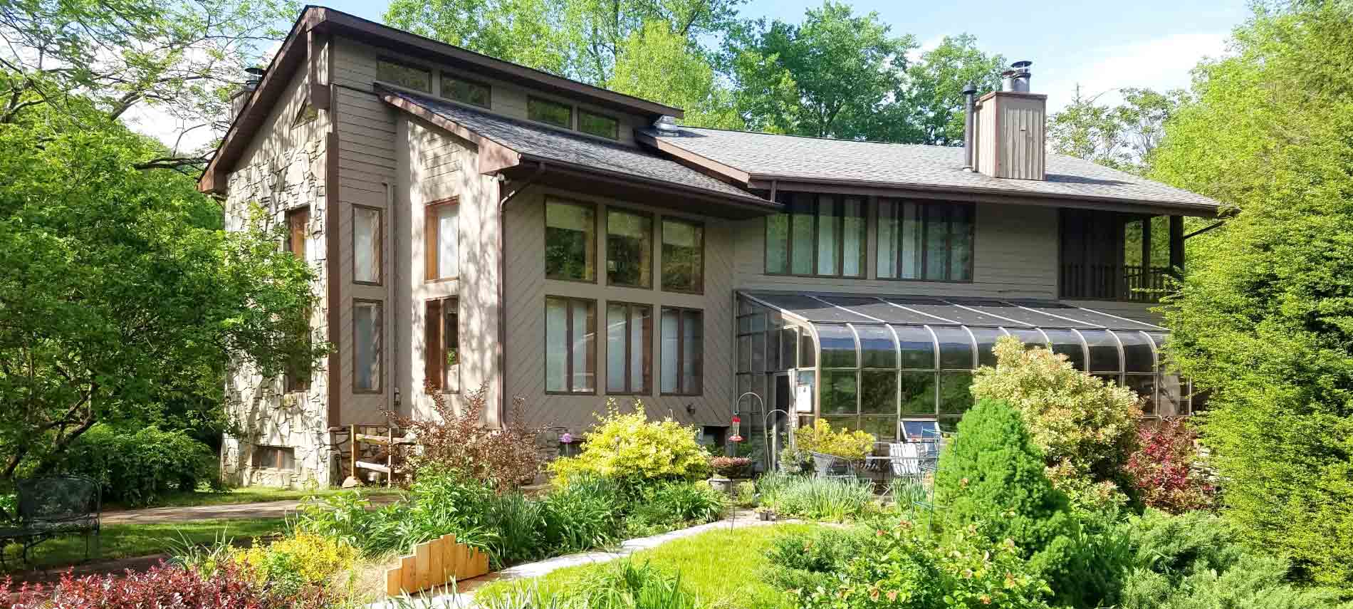 Exterior of the inn with gardens and landscaping underneath houses many windows and sunporch dining area. 