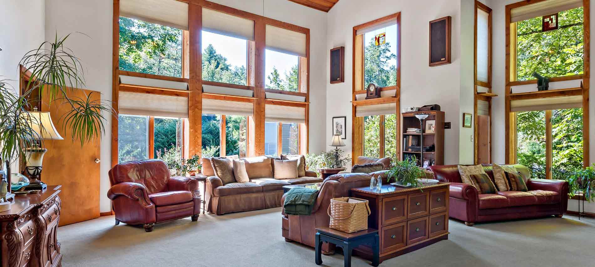 Spacious interior sitting area with multiple couches and love seats underneath high ceiling with tall windows allowing in sunlight.