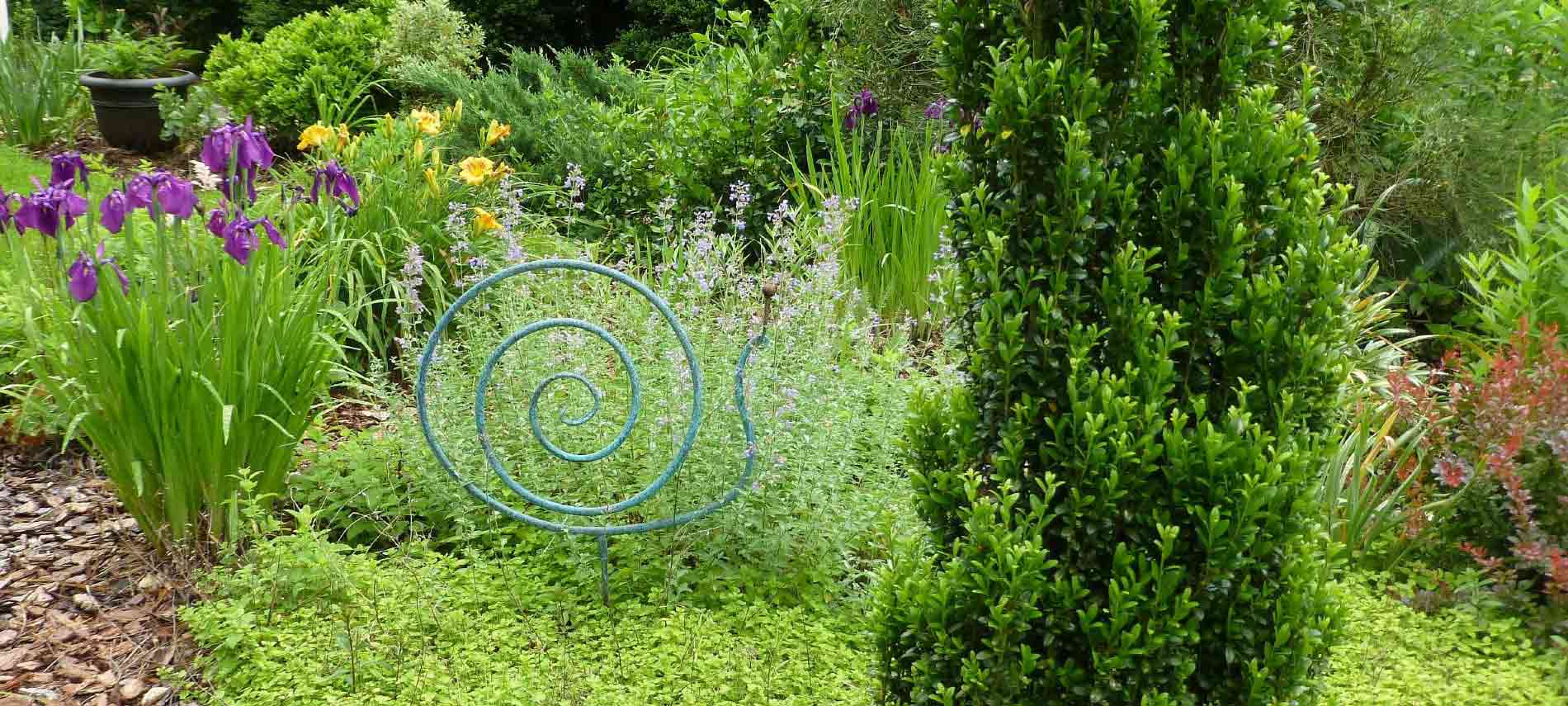 Garden area on the grounds outside the main building showcasing purple and yellow flowers and sculpted green shrub.