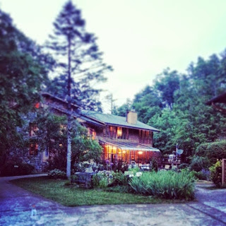 Lodge style bed and breakfast surrounded by trees at twilight