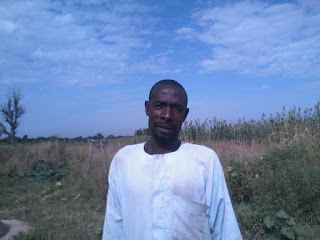 Nigerian farmer with a white shirt standing outside in a field