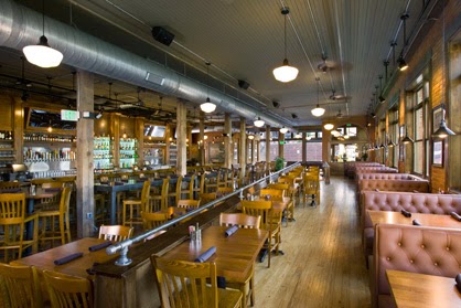 Restaurant with booths on one side, tables in the center and an upscale bar on the other side