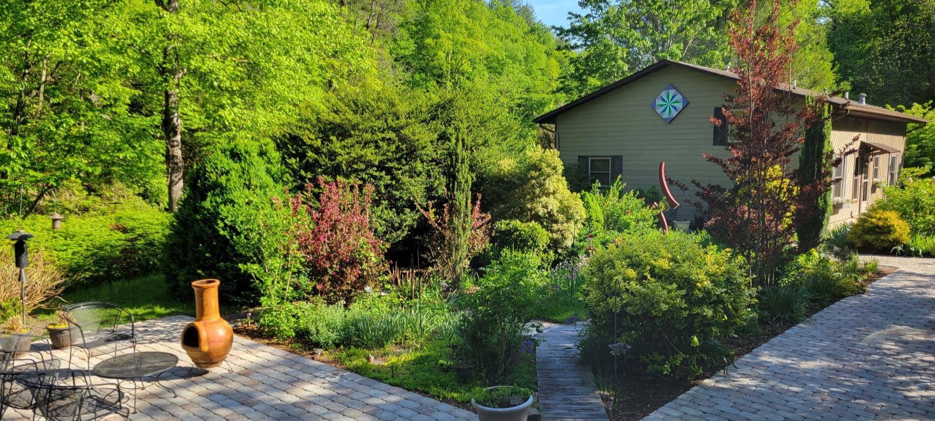 patio area with black metal table and chairs in the garden with cottage in distance