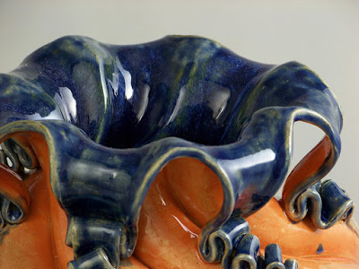 Top of a curvy ceramic pitcher that is dark blue on the inside and orange on the outside